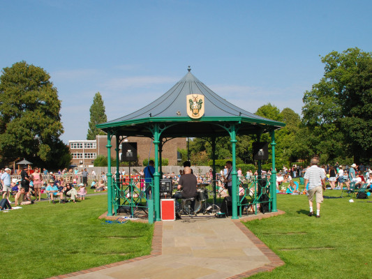 People watching a band play in a bandstand in a park.