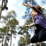 Girl leaping in the air. Tall trees in background