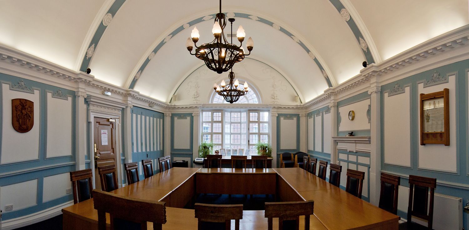 Large blue and white room. Wooden tables with chairs around the outside.