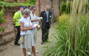 Male and female with clipboards looking at plants in garden.