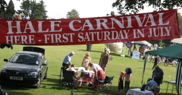 Banner advertising Hale Carnival. People setting up stalls for fete.