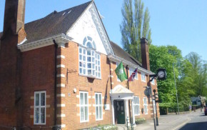 exterior of red brick building, flags and clock on the side.