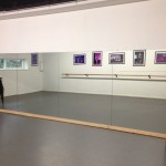 Interior view of dance studio with mirrored wall and red curtain to side. Reflection of wall barre on wall