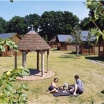 male and female having a picnic, wooden lodges in back ground