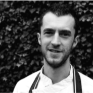 Black and white head and shoulders photo of man wearing chef's whites. © The Wheatsheaf Pub & Grill