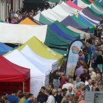 Aerial view of people and colourful market stalls at Food Festival held in street.