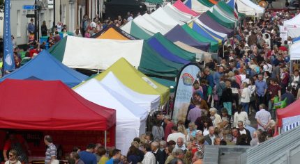 Aerial view of people and colourful market stalls at Food Festival held in street.