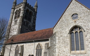 Stone church with red tiled roof. Tower, arched windows