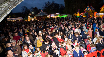 Crowd of people, bouncy castles and stalls in the background.