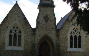 Outside stone chapel, bell turret, arched windows and door.