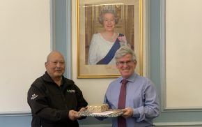 Man presents gift wrapped items to man on his right.