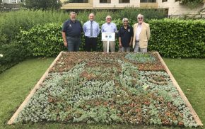 Five people standing behind a flower bed