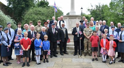 Group of adults and children standing in front of war memorial