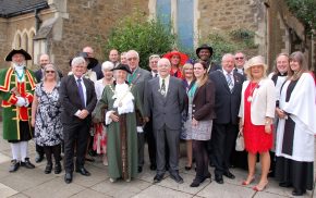 Mayor with group of people in smart clothes standing outside church.