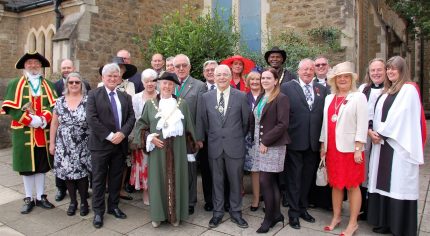 Mayor with group of people in smart clothes standing outside church.