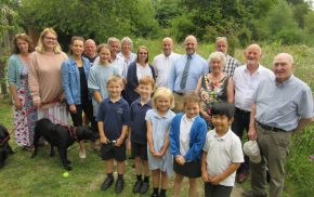 Group of adults and children in a green space.