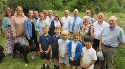 Group of adults and children in a green space.