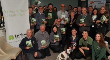 Group of people holding a booklet. Dog in foreground