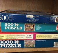 Four boxes of jigsaw puzzles stacked in a pile