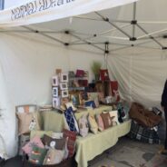Market stall displaying cushions and craft items.