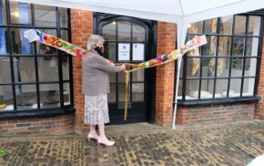 Female cuts a ribbon to mark the opening of a shop.